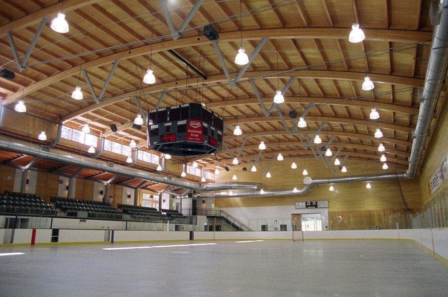 The empty ice at Armstrong's hockey arena, beneath its vaulted wood-beam roof